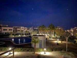 uma piscina à noite com edifícios e palmeiras em Piso de lujo - descansar y trabajar en Golf Panoramica para 4 pers - internet fibra GRATIS em Sant Jordi