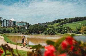 a woman riding a bike next to a river at Fazzenda Park Resort in Gaspar