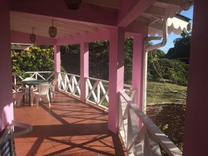 a pink porch with a table and chairs on it at The Pink House in Choiseul