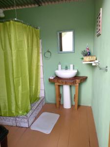 baño con lavabo y cortina de ducha verde en Glamping Naioth, en Guápiles