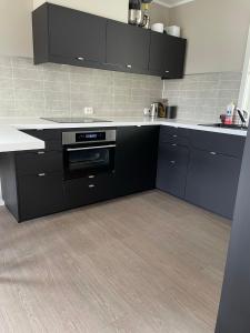 a kitchen with black cabinets and white counter tops at Hus med 2 soverom in Sortland