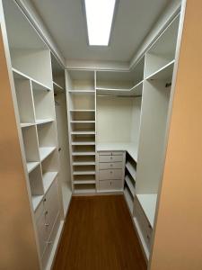 a walk in closet with white shelves and a skylight at Suíte no Jardim Botânico in Rio de Janeiro