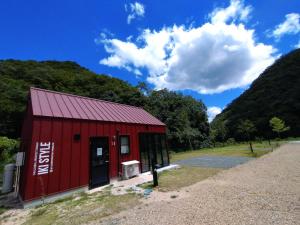 um celeiro vermelho com um céu azul e montanhas em Ayu no Sato Park Campsite - Vacation STAY 42166v em Shōbara