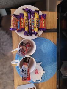 Chocolates&Flowers في Leverstock Green: طاولة بها طبقين من الرقائق وكوبين