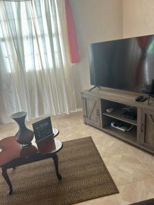 uma sala de estar com uma televisão de ecrã plano e uma cadeira em StayHaven Escapes em Saint Michael
