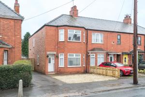 a red brick house with a red car parked outside at Rio's Retreat in Cottingham