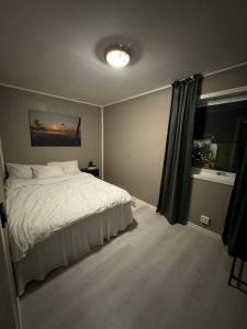 a bedroom with a white bed and a window at Hus med 2 soverom in Sortland