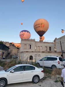 a white car parked in front of a building with hot air balloons at Göreme Escape Cave Suites in Goreme
