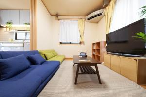 a living room with a blue couch and a flat screen tv at Lucky Higashi Mizue - Vacation STAY 16180 in Tokyo