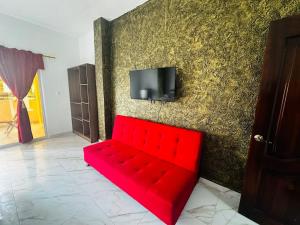 a red couch in front of a wall with a tv at Casa Palmamar in Olón