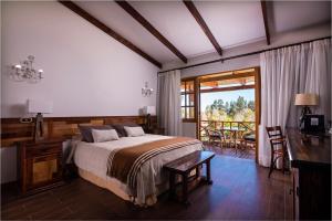 a bedroom with a bed and a desk and a balcony at Hacienda Santa Cristina in Ovalle