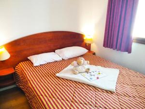 un osito de peluche sentado encima de una cama en Résidence Pic Du Midi - 2 Pièces pour 4 Personnes 684, en La Mongie