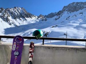 a snowboard leaning against a rail with a snow covered mountain at Résidence Pic Du Midi - 2 Pièces pour 4 Personnes 694 in La Mongie