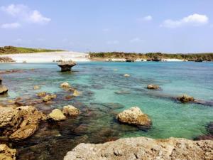 een strand met rotsen en blauw water en een strand bij Yoron Tandy-House - Vacation STAY 78660v in Yoron