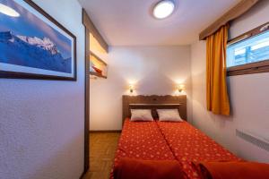 a small bedroom with a red bed with two pillows at Charmant appartement 2 Pièces Cabine 4-6 Personnes in Chamrousse
