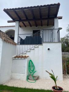 a white house with a staircase with a green hose at Gibilo's home in Bari Sardo