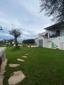 a grass yard with a house and a tree at Gibilo's home in Bari Sardo