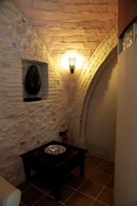 Habitación con pared de piedra, mesa y luz. en Viña Zarzarrosa Osuna, en Osuna