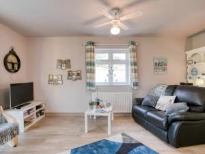 a living room with a leather couch and a tv at 2 Bed in Bridlington 77607 in Sewerby