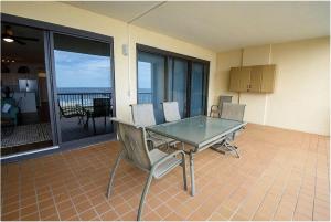 een glazen tafel en stoelen in een kamer met een balkon bij Grand Pointe Unit 613 in Orange Beach