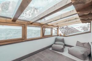Habitación con sofá y ventanas con vistas a las montañas. en Hotel Piz Seteur, en Selva di Val Gardena