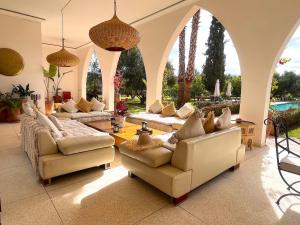 ein Wohnzimmer mit Sofas und Stühlen sowie einem Pool in der Unterkunft Palais Dobra in Marrakesch