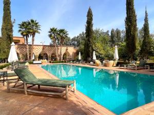 einen Pool mit Stühlen und Sonnenschirmen in der Unterkunft Palais Dobra in Marrakesch
