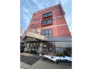 un edificio rosa alto con un cartel. en Towada City Hotel - Vacation STAY 85224v en Towada