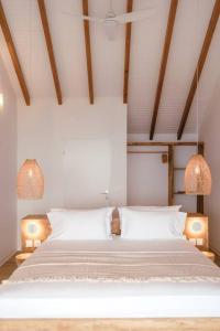 een slaapkamer met een groot wit bed met 2 lampen bij Vaneïa : Vue mer panoramique depuis un duplex d'exception in Bouillante