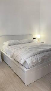 uma cama branca num quarto branco com um candeeiro em Sidra chalet 