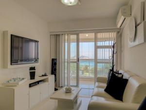 a living room with a couch and a tv at LINKHOUSE LUXURY BEACHFRONT FLATS in Rio de Janeiro