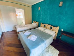een slaapkamer met 2 bedden en een blauwe muur bij Hotel Beira Rio Guararema in Guararema