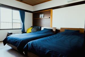 1 Schlafzimmer mit 2 Betten mit blauer Bettwäsche und einem Fenster in der Unterkunft Atami-Ajironokaze - Vacation STAY 87959v in Atami