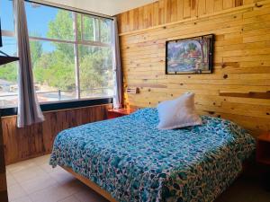 een slaapkamer met een bed in een houten muur bij Parque Cueva de los Leones - Rimusa Inn in Creel