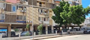 ein Gebäude an der Seite einer Straße mit einem Baum in der Unterkunft Pimenova Residence in Luanda