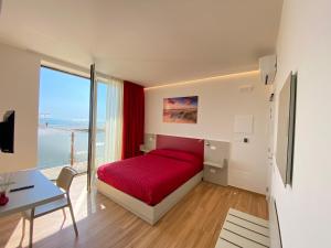 a bedroom with a red bed and a table and a desk at Bagno Luciano in Marina di Carrara
