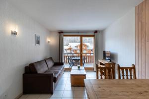 un soggiorno con divano e tavolo di Résidence Le Balcon Des Airelles - 2 Pièces pour 4 Personnes 334 a Les Orres