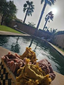 een mand met eten naast een zwembad met water bij Villa Naya et sa Piscine chauffée sans vis-à-vis in Agadir