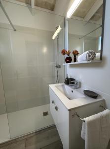 y baño blanco con lavabo y ducha. en Apartamentos Islanders, en Cala en Forcat