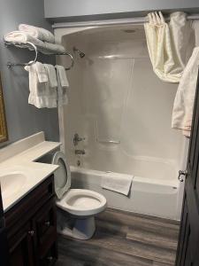 een badkamer met een toilet, een bad en een wastafel bij Gamble Farm Inn and Suites 