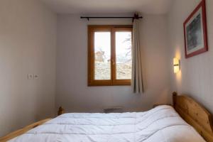a bedroom with a white bed and a window at Résidence Le Balcon Des Airelles - 2 Pièces pour 4 Personnes 574 in Les Orres