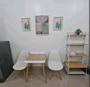 une table, deux chaises blanches et une étagère dans l'établissement HOMELY Green 2 residences DLSU EAC UMC, à Dasmariñas