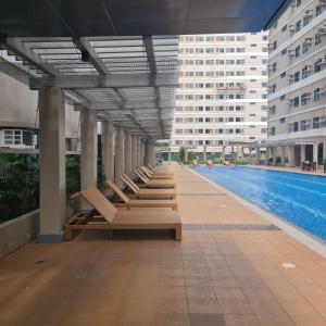 - une rangée de chaises longues à côté de la piscine dans l'établissement HOMELY Green 2 residences DLSU EAC UMC, à Dasmariñas
