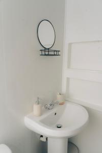 W białej łazience znajduje się umywalka i lustro. w obiekcie Mideyah Stays - 3 Bed Comfy House w Cardiff