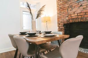 comedor con mesa, sillas y chimenea de ladrillo en Mideyah Stays - 3 Bed Comfy House, en Cardiff
