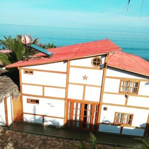 ein weißes Gebäude mit rotem Dach und Meer in der Unterkunft Kalua Plateritos in Plateritos