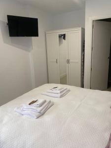 two white towels sitting on a bed with a mirror at Apartamento Baeza 4A in Baeza