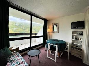 a hotel room with a table and a large window at Résidence Tougnette - Studio pour 3 Personnes 494 in Les Menuires