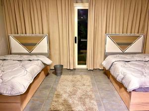 - 2 lits dans une chambre avec des rideaux et un tapis dans l'établissement Cozy Studio W.Private Heated swimming pool in New Cairo, au Caire