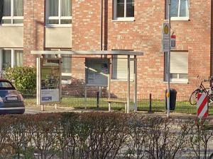 una parada de autobús con un banco frente a un edificio en gemütliches Dachgeschoss en Bonn